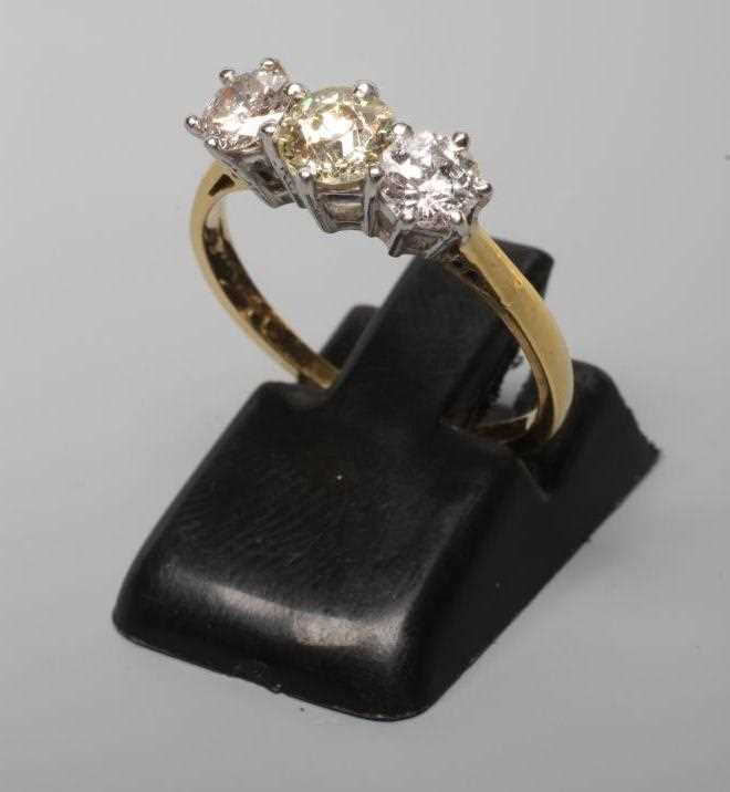 A THREE STONE DIAMOND RING, the central old cut stone flanked by two similar smaller stones