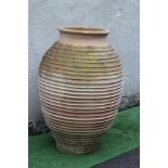 A LARGE TERRACOTTA OLIVE JAR of ovoid form with ribbed banding, 55" high (Est. plus 24% premium inc.