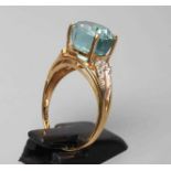 A BLUE TOPAZ COCKTAIL RING, the oval facet cut stone horizontally claw set to open bead shoulders