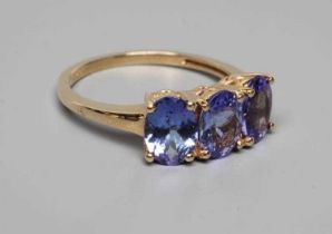 A THREE STONE TANZANITE RING, the oval facet cut stones claw set to a plain shank, stamped 14k, 585,