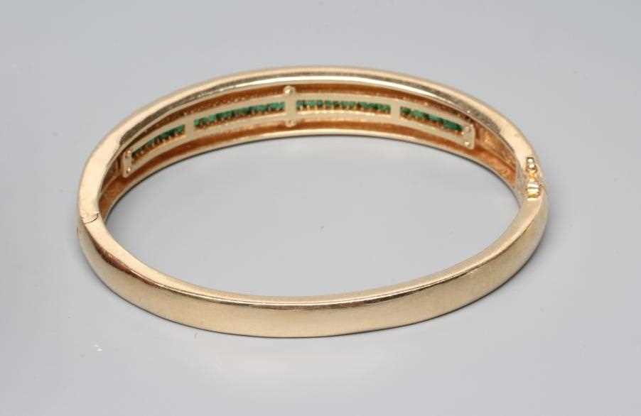 AN EMERALD STIFF HINGED BANGLE, the upper section channel set with twenty two graduated calibre - Image 3 of 3