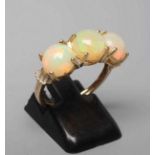 A THREE STONE OPAL RING, the round cabochon polished stones claw set to a plain 14ct gold shank,