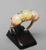 A THREE STONE OPAL RING, the round cabochon polished stones claw set to a plain 14ct gold shank,