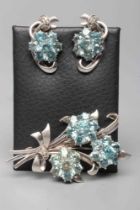 A BLUE TOPAZ TRIPLE FLOWER SPRAY BROOCH, the nine stone flowerhead clusters set to a white frame