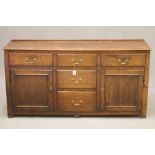 AN OAK ENCLOSED DRESSER, early 19th century, the moulded edged top with rear plate stay, the