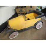 A vintage Brum pedal car, of metal construction with classic yellow body paint, forward crank