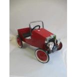 A reproduction pedal car, in the 1930s style, of metal construction painted in red, with two tone