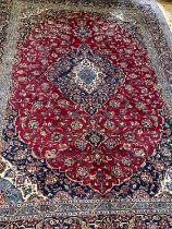 A KASHAN CARPET, the crimson floral field with central ivory and blue gul and spandrels within an