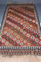 A KILIM RUG, the madder field with diagonal rows of diamonds in alternating colours of shades of