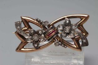 AN ART DECO DIAMOND AND RUBY BOW BROOCH, the angular loops centred by a convex row of five channel
