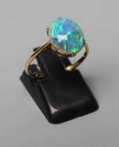 T. GAUNT - a black opal ring, the oval cabochon polished stone claw set to a plain shank, stamped