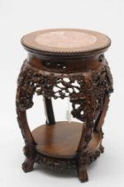 A CHINESE PADOUK WOOD STAND, c.1900, the beaded edged circular top inset with rouge marble, arched