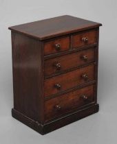 A MAHOGANY MINIATURE CHEST, early/mid 19th century, of two short over three long drawers with turned