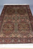 A PERSIAN SILK RUG, the pale green floral field with four oval guls with exotic birds, within an