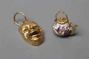 A CHARM/PENDANT, stamped 750/GB, cast and pierced as the theatrical comedy mask with matt finish,