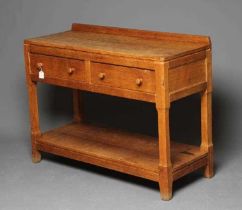 A PETER HEAP ADZED OAK SIDE TABLE, the moulded edged canted oblong top with ledge back, two frieze