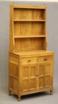 A WILFRED HUTCHINSON (HUSTWAITE) ADZED OAK SMALL DRESSER, the boarded delft rack with half penny