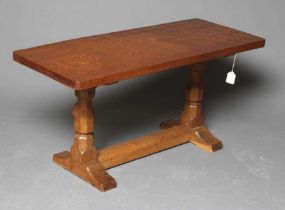 A ROBERT THOMPSON ADZED OAK COFFEE TABLE, the rounded oblong plank top on trestle base with