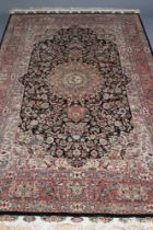 A PERSIAN RUG, the black field with rose pink gul and ivory spandrels within a pale blue border with