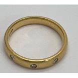 An 18 carat diamond set gold wedding band. Weight 4.9gm. Size P. Marked 750.