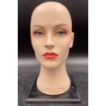 A painted Zepla mannequin head on stand, 31cm h with false eyelashes