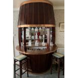 A vintage mahogany and copper barrel shaped bar. 240cm h x 90cm d x 171cm w. Spirits and glassware