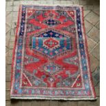 A wool rug with red and blue ground geometric design. 142 x 103cm.