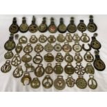 A collection of horse brasses some on leather straps and some individual.