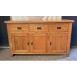 An oak sideboard, three drawers over three doors. 87 h x 149 w x 44cm d.