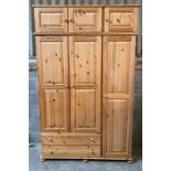 A large pine wardrobe with a combination of three doors over two drawers and a removable 3
