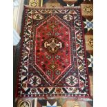 A vintage wool rug in shades of red. 122 l x 83cm w.