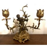 A brass and ormolu two branch candelabra with cherub to the centre. 20cm h.
