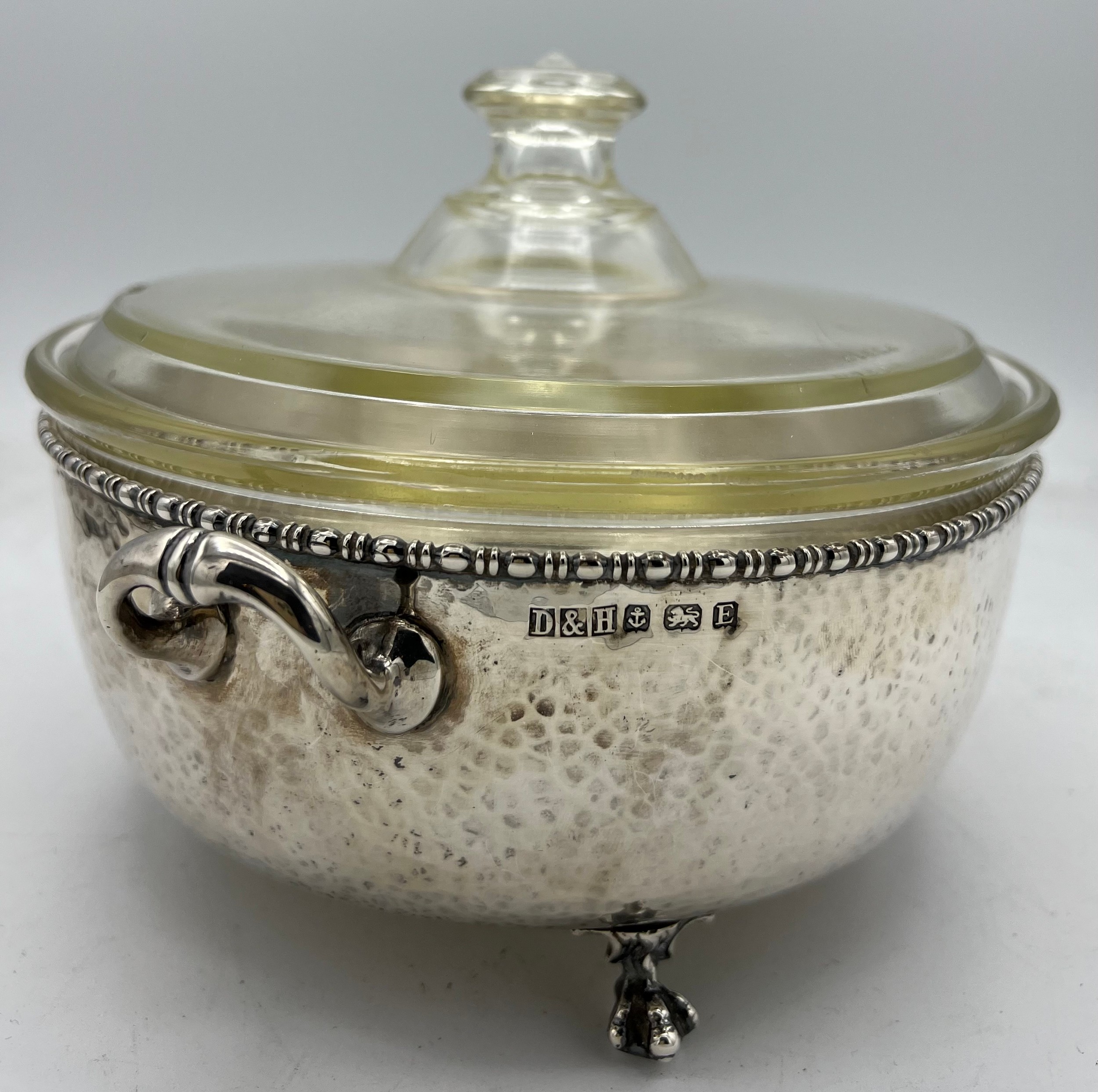 A twin handled hammered silver dish holder raised on paw feet with lidded Pyrex dish. Birmingham