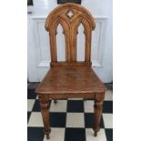 An oak Gothic style hall chair. Ht to back 86cm, to seat 42cm.