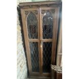 A carved oak 2 door cabinet with leaded and stained glass, 6 shelves. 69 x 32 d x 185cm h.