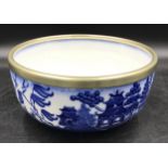 A Mintons blue and white bowl decorated in the willow pattern with white metal collar around rim,