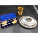 A boxed pair of silverplate berry spoons, lidded tureen and a horn beaker with white metal collar.