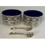 A pair of hallmarked silver pierced salt sellers with original spoons and blue glass linings
