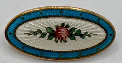 An Edwardian oval enamel brooch depicting a pink rose on a white background within a turquoise