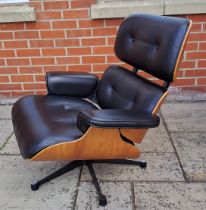 An Eames style armchair covered in black leather. 82cm h x 85cm w x 72cm d.