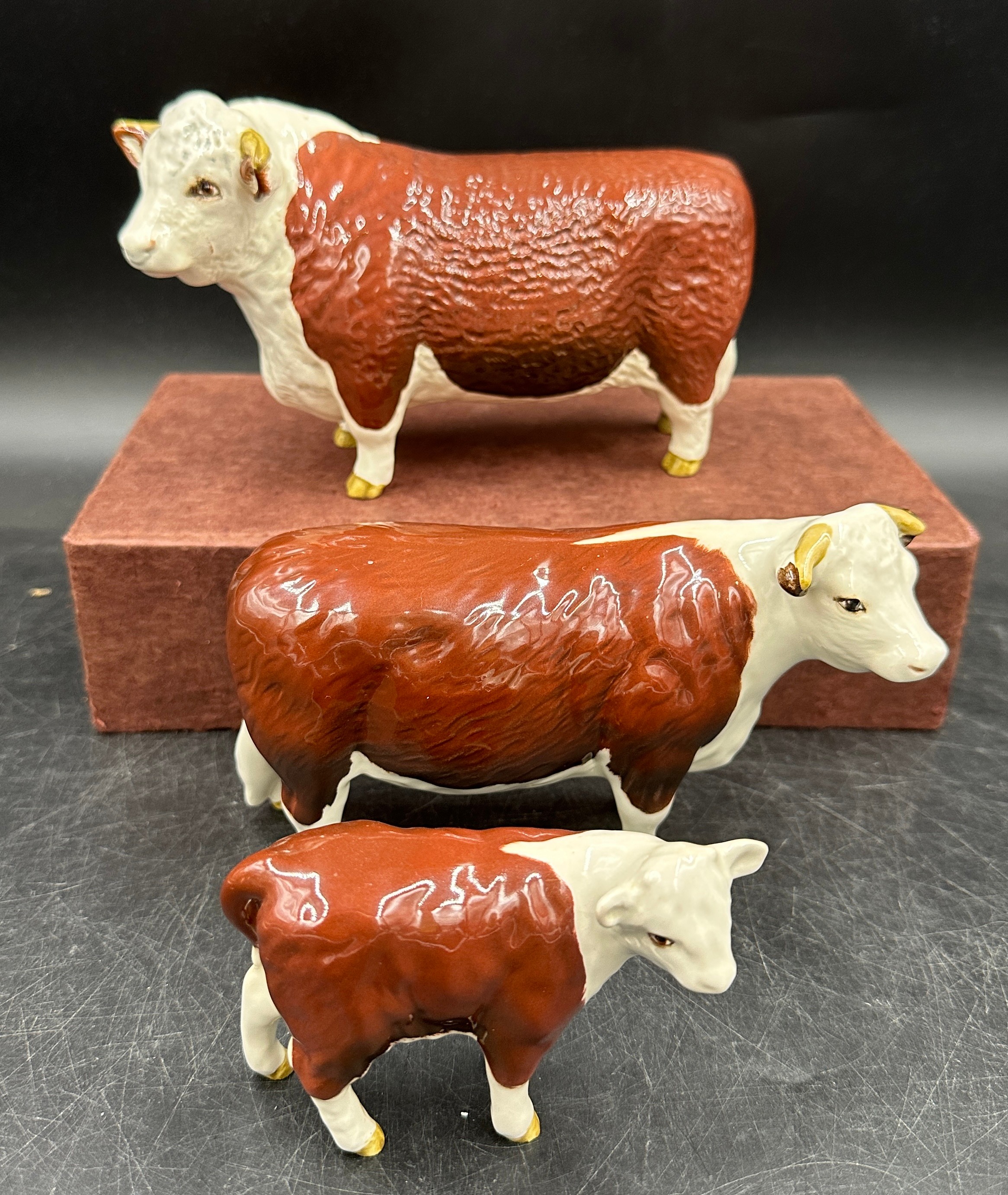 Two Beswick Ch. of Champions - Hereford Bull 10cm h and cow figurines together with a calf. All