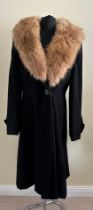 A ladies black coat with a fur collar with 'Marlbeck Model' label and button details to the cuff