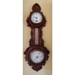 A carved oak aneroid barometer, mercurial thermometer and clock. Circa 1900. 66cm h x 27w.