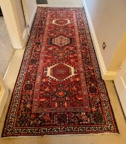 Wool red ground rug made in Iran 281cm x 112cm.