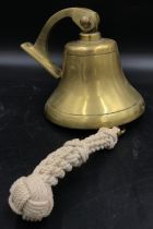 A large unmarked ships bell with wall attachment with woven rope still attached approx 18cm h