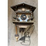 A vintage Swiss made wooden cuckoo clock with metal weights. 20cm h.