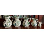 Five graduated Masons jugs in Chartreuse pattern. Largest 17cm h.