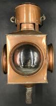 A large copper signal lamp containing four lenses, two red, two clear, one of which has concentric
