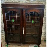 An oak 2 door bookcase with leaded glass doors on short cabriole legs. 105 h x 85 w x 26cm d.