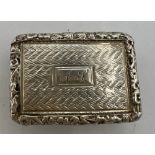 A hallmarked silver vinaigrette with engine turned decoration, cast foliage border and monogrammed
